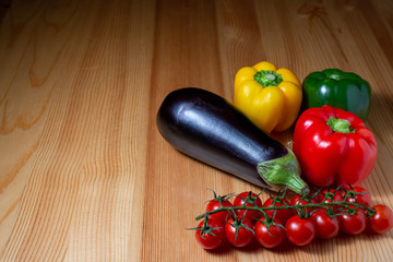 eggplant, paprika and cherry tomatoes on a wooden kitchen table