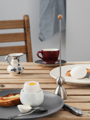 Two soft-boiled eggs, white eggs on a wooden brown table. Gray ceramic plate with soft-boiled egg, fried toast with butter. A cup of coffee. Morning, healthy continental breakfast for two. Close-up.
