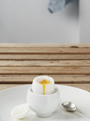 Soft-boiled egg, white egg on a wooden brown table. White ceramic plate with soft-boiled egg. Morning, healthy breakfast. Close-up. Copy space