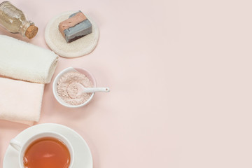 Creative flat lay of bath accessories beauty spa concept with copy space handmade soap rose and clay mask top view cup of tea