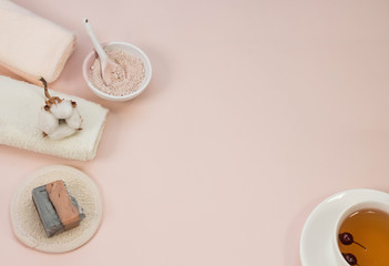 Creative flat lay of bath accessories beauty spa concept with copy space handmade soap rose and clay mask top view cup of tea