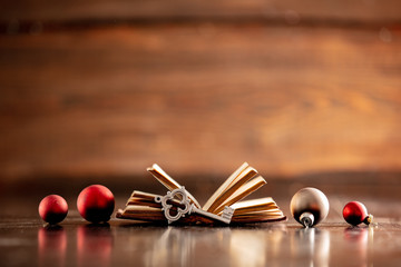Old book with key and Christmas baubles on wooden table