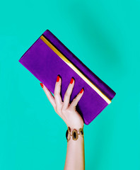 Purple purse wallet with beautiful woman hand isolated on green background