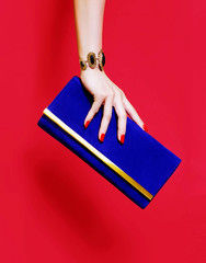 Beautiful hand with red manicure holding a purse wallet on red background  - 308307770