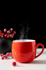 Winter or christmas cozy composition, steaming cup coffee or hot drink, Xmas decoration on black background. Christmas, New Year, winter concept. Front view, copy space