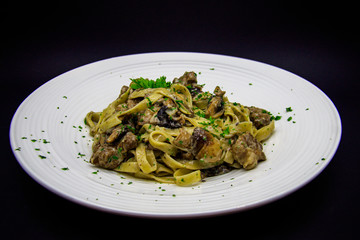 Pasta with mushrooms and pork on a black background