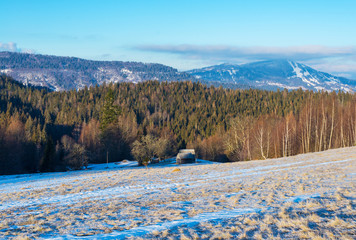 Snow-covered mountainside against the background of forest-covered mountains.