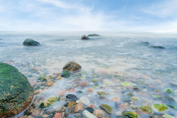 A view of the rocky beach in Miedzyzdroje. Baltic sea. Stones into the water. Blurry effect with long exposure.