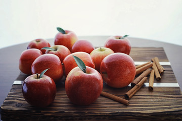 Fresh apples on a wooden board. Harvest of red apples. Fruits and cinnamon on the table.