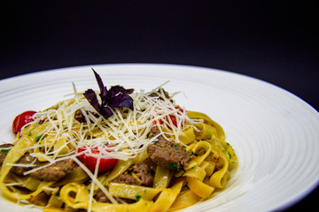Pasta with beef and cherry tomatoes on black background