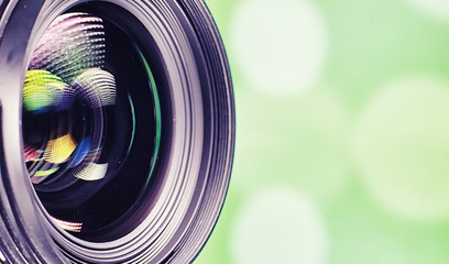 Equipment videographer and photographer. Lenses on the table against the background of bright lamps. Glare and bokeh in reflection of camera glass.
