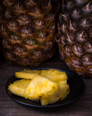 Sliced pineapple on old rustic desk Black background.