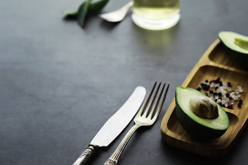 Avocado cooking recipes. Ripe green avocado on a wooden cutting board for serving.