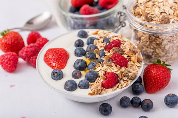 Yogurt in white bowl with strawberries and blueberries on white background.Yogurt in white bowl with strawberries and blueberries on white background.
