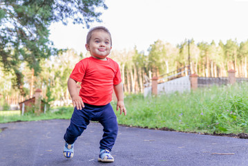Fototapeta premium portrait of smiling little boy on the street. cute cheerful baby walking in the Park. happy child