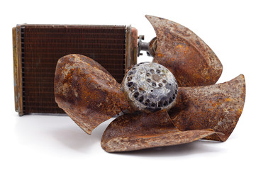 Old propeller with pile of scrap metal and radiator.