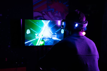 virtual reality game in helmet with luminous controllers. front of the TV
