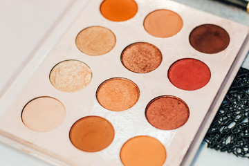Cosmetic products on the table by a professional makeup artist in the salon. Palette of shadows nude and gold
