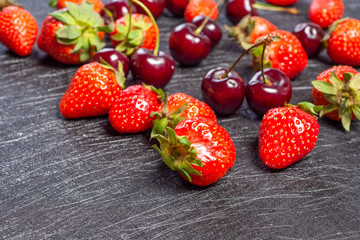 Fresh cherries and strawberries on a black background - 308315921