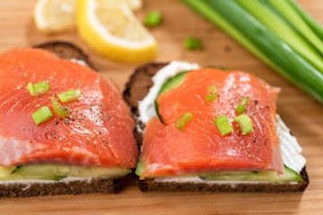 Smoked salmon sandwiches with rye bread, cream cheese and cucumber. Closeup view