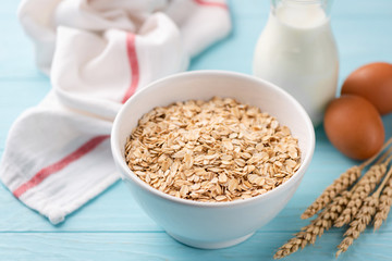 Oats, milk and eggs on blue wooden table. Food ingredients for a healthy breakfast