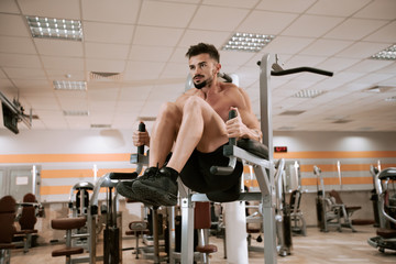 In a modern gym muscular man doing exercises for his triceps concentrated working hard