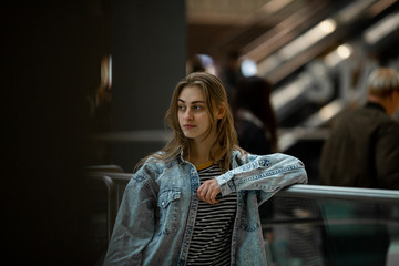 Teenager. Young pretty white caucasian teenage girl with long hair with problem skin and long hair in a shopping center near the railing.