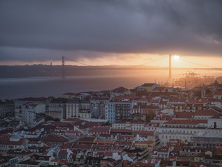 Views of the city of Lisbon at sunset from St George's Castle, with Abirl Bridge 25 in the background.