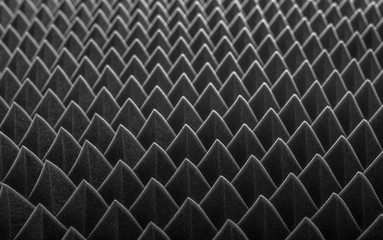 Abstract background in the form of pyramids and dragon scales. Acoustic black foam rubber.