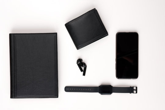 Men's collection. Black leather diary, black pen, smart watch, smartphone and headphones on a white background. View from above. - Powered by Adobe