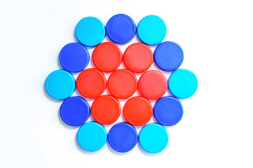 Plastic multi-colored caps laid out in the shape of a figure for bottles on a white background. Close-up.