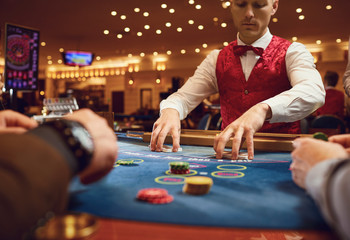 Gambling in a casino. The croupier holds poker cards in a casino.