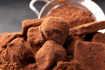 Macro chocolate truffles with cocoa in wooden plate on table on dark background. Copy space