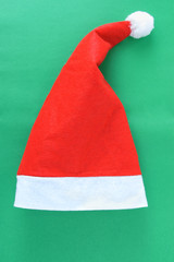Christmas red Santa hat on a green background. Vertical photo