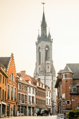 Fototapeta na wymiar Tall medieval bell tower rising over the street with old european houses, Tournai, Walloon municipality, Belgium