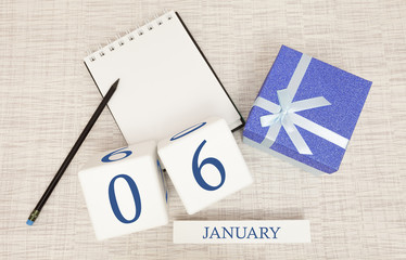 Calendar with trendy blue text and numbers for January 6 and a gift in a box.