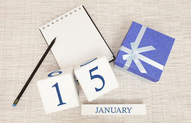 Calendar with trendy blue text and numbers for January 15 and a gift in a box.