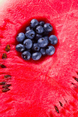 Watermelon and blueberries on white background. The process of eating watermelon with a spoon. Blueberries in watermelon. Creative food concept