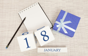Calendar with trendy blue text and numbers for January 18 and a gift in a box.