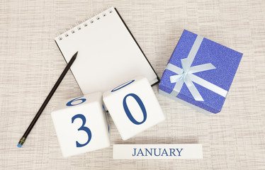 Calendar with trendy blue text and numbers for January 30 and a gift in a box.