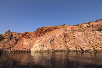 Fototapeta na wymiar Volcanic rocky red cliffs in Milos, Greece