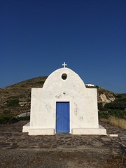 White building with blue door in Milos, Greece