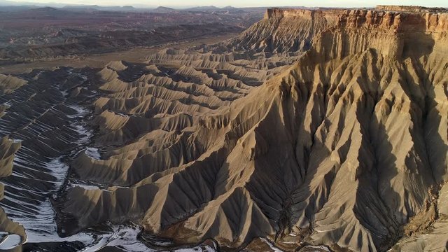 Flying along cliffs above the rugged terrain as the landscape glows in the vast desert in Utah.