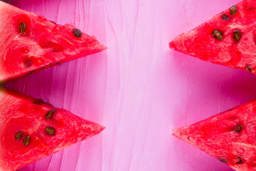 Slices of watermelon on pink background. Sliced watermelon with seeds. Creative food concept. Top view. Copy space