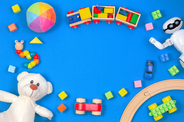 Obraz premium Kids toys background. White teddy bear, wooden train, toy car, robot, colorful blocks on blue background
