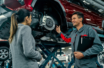Beautiful businesswoman and auto service mechanic are discussing the work. Car repair and...