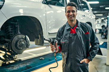 Handsome mechanic in uniform is working in auto service. Car repair and maintenance....