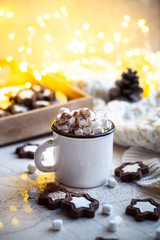 Comforting Christmas food, mug of hot cocoa with marshmallow and cookies with cozy lights