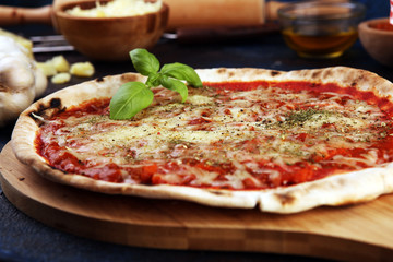 Pizza with tomatoes, mozzarella cheese, basil. Delicious italian pizza on wooden pizza board.