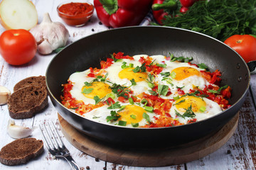 Shakshouka with five cooked eggs on top of tomato sauce in cast iron skillet	